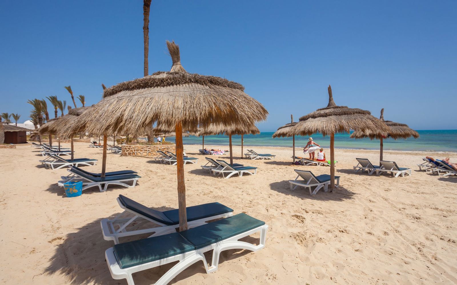 Thatched parasols and sun loungers on the beach at Djerba - Just Sunshine Holidays